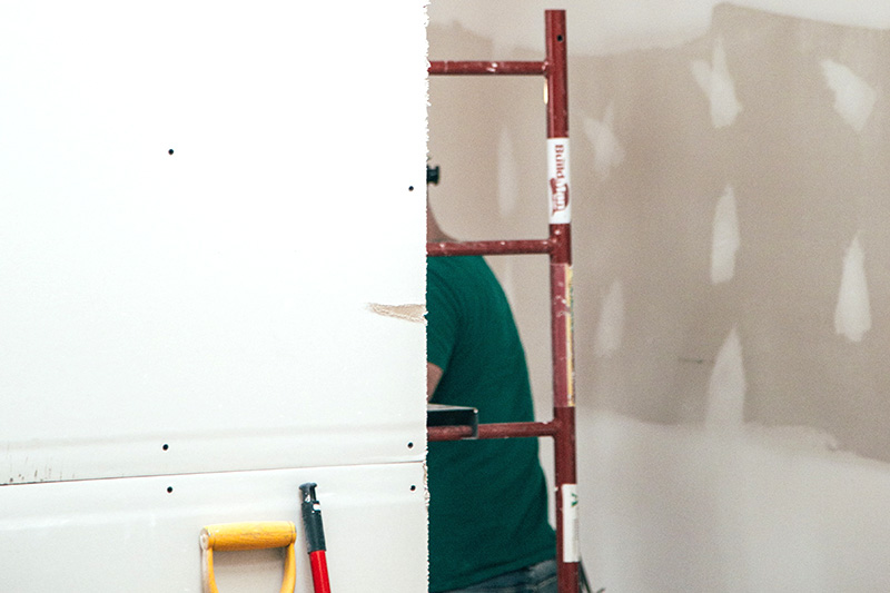Drywall installation inside a custom shipping container office.